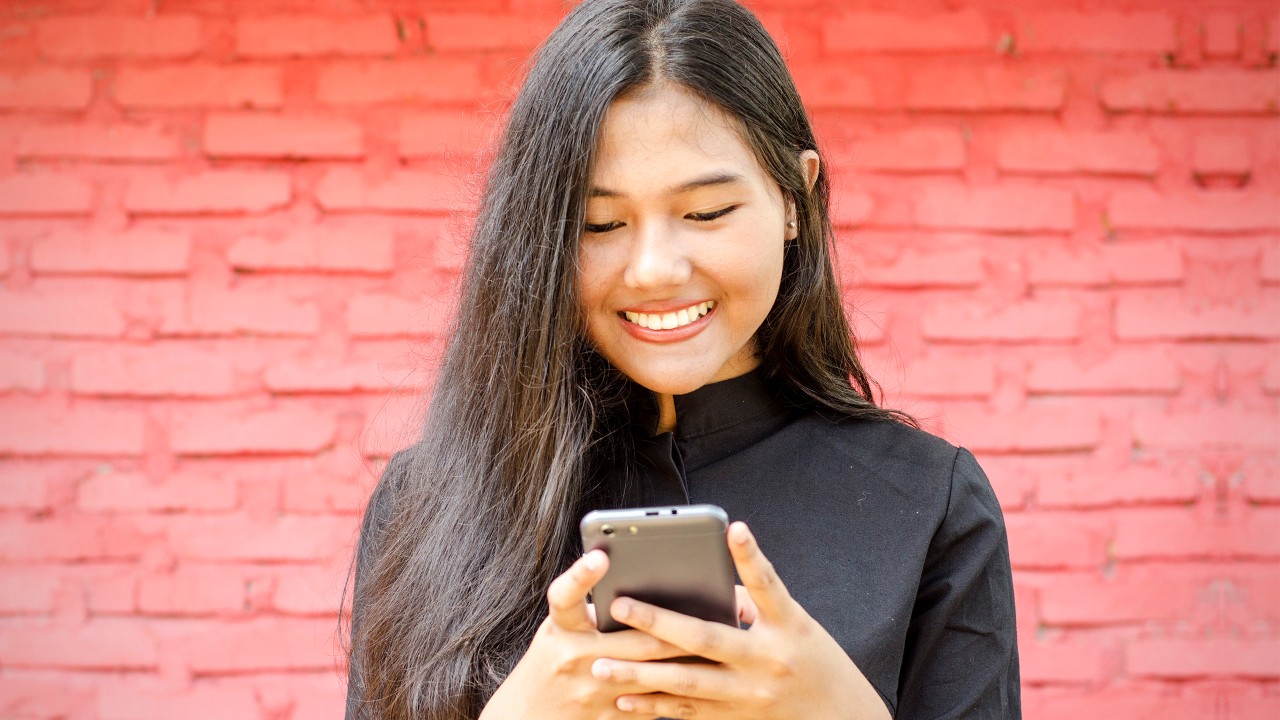 一個女孩正在使用她的手機; 圖片使用於滙豐Reward+的頁面。