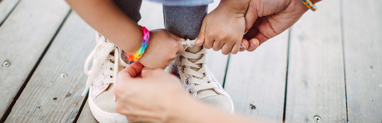 Helping little girl to tie her shoelace; image used for HSBC Frequently asked questions (FAQs) page.