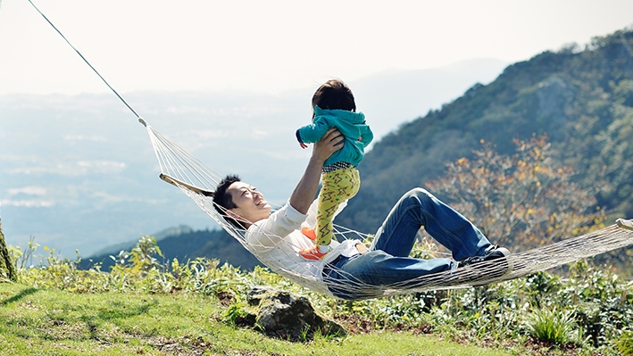 爸爸躺在吊床上抱著他的小孩；圖片使用於滙豐人壽保險頁面。