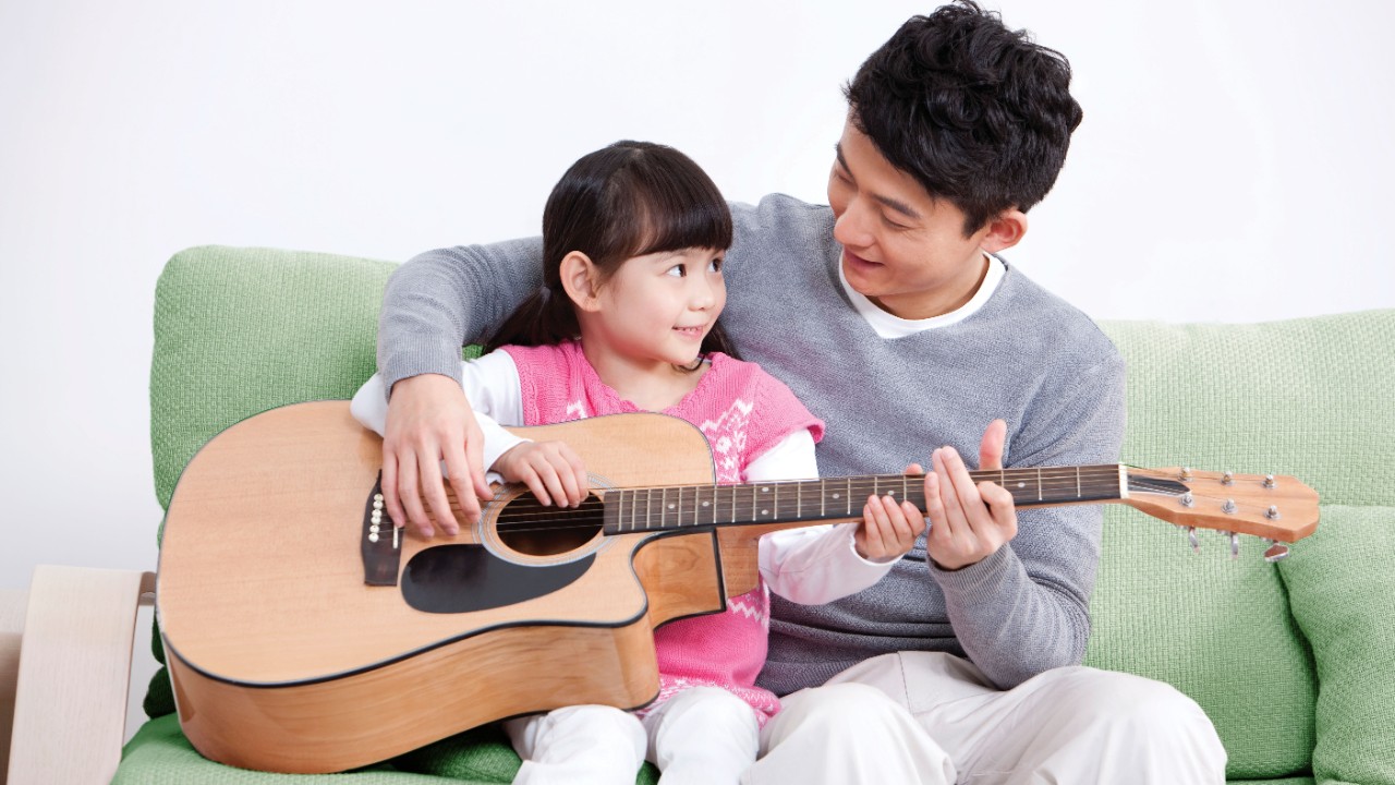 Father and daughter playing guitar; image used for HSBC Goal Access Life Education Plan .