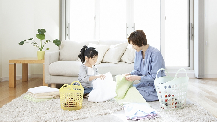 女兒在幫媽媽摺疊衣服；圖片使用於家傭綜合保險頁面。