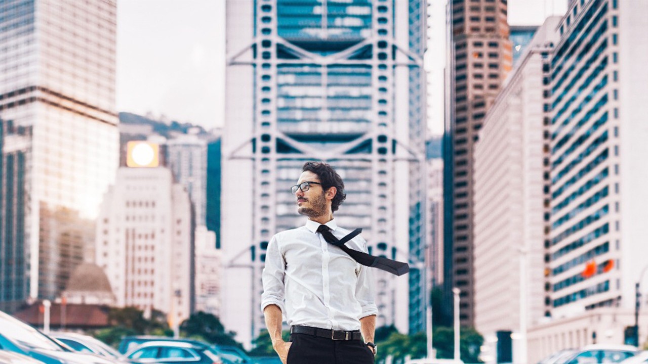 A man stands in the middle of skyscrapers; image used for local lifestyle guide greeting.