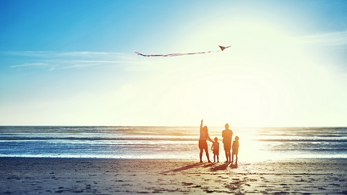 一個家庭在沙灘旁邊放風箏；圖片使用於滙豐保障的力量頁面。