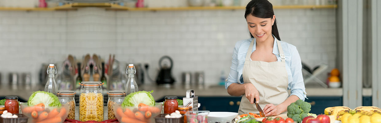 A woman is cooking in the kitchen, image used for "How much does it cost to become a master chef" article 