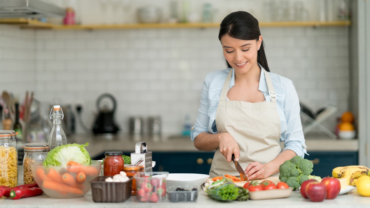 A woman is cooking in the kitchen, image used for "How much does it cost to become a master chef" article