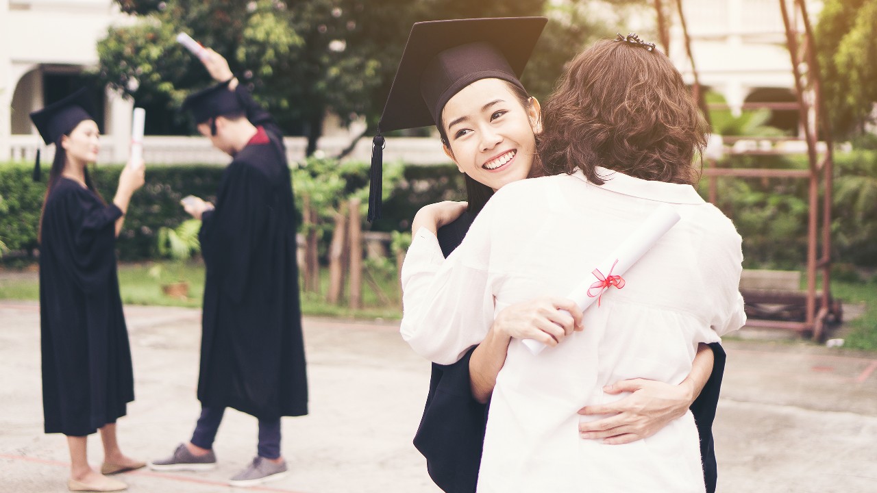 女儿在毕业典礼上拥抱她的母亲，图像用于"子女海外升读大学如何准备？开支要多少？"的文章