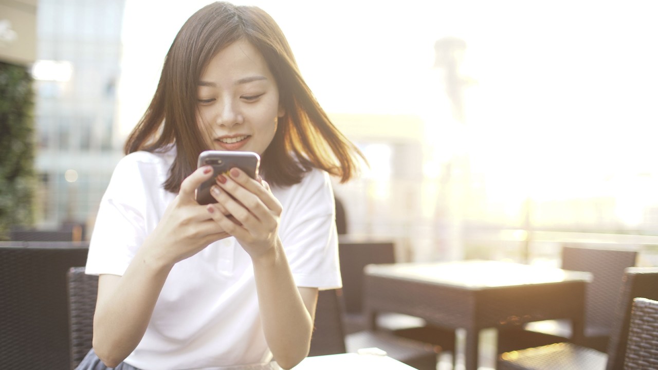 A girl is looking at the phone，image used for mobile trading app page.