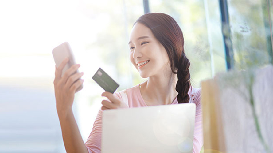 A lady uses a credit card to shop online through her mobile phone; image used for HSBC Reward+ Mobile App.