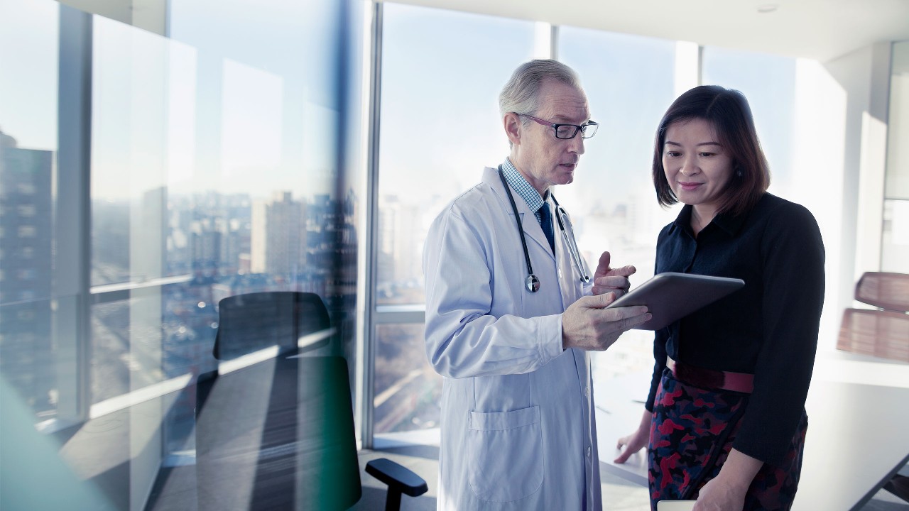 医生在与病人用平板电脑交流；图片使用于“优越医护计划”医疗保险页面。