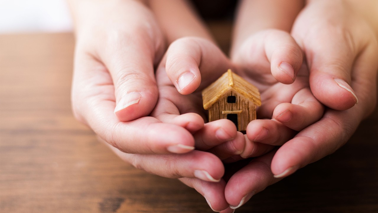 Close up of woman and girl holding model house; image used for HSBC ResidenceSurance.