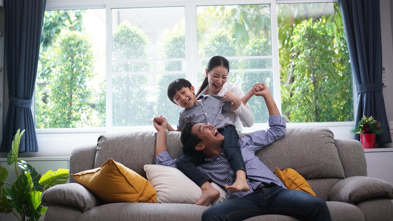 一家人在一起玩，父親給他的兒子背騎；圖片使用於家居超卓萬全保。
