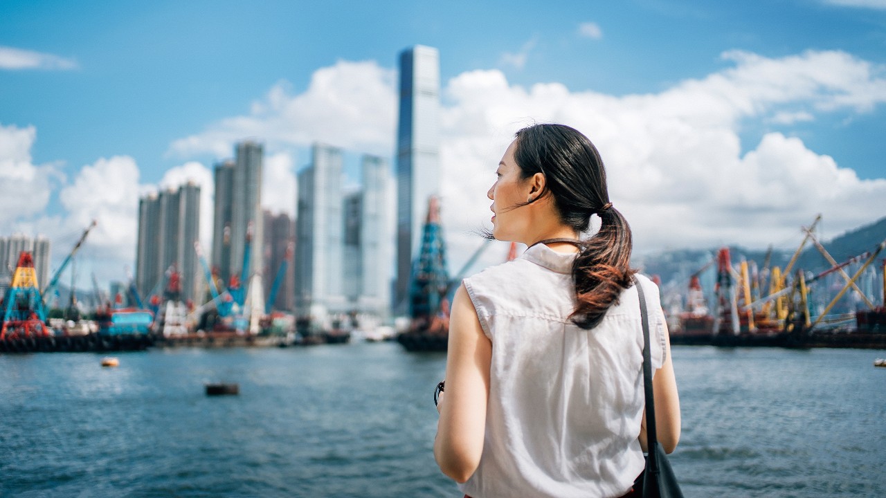 女士正在俯瞰城市景观；图片使用于香港本地银行服务。