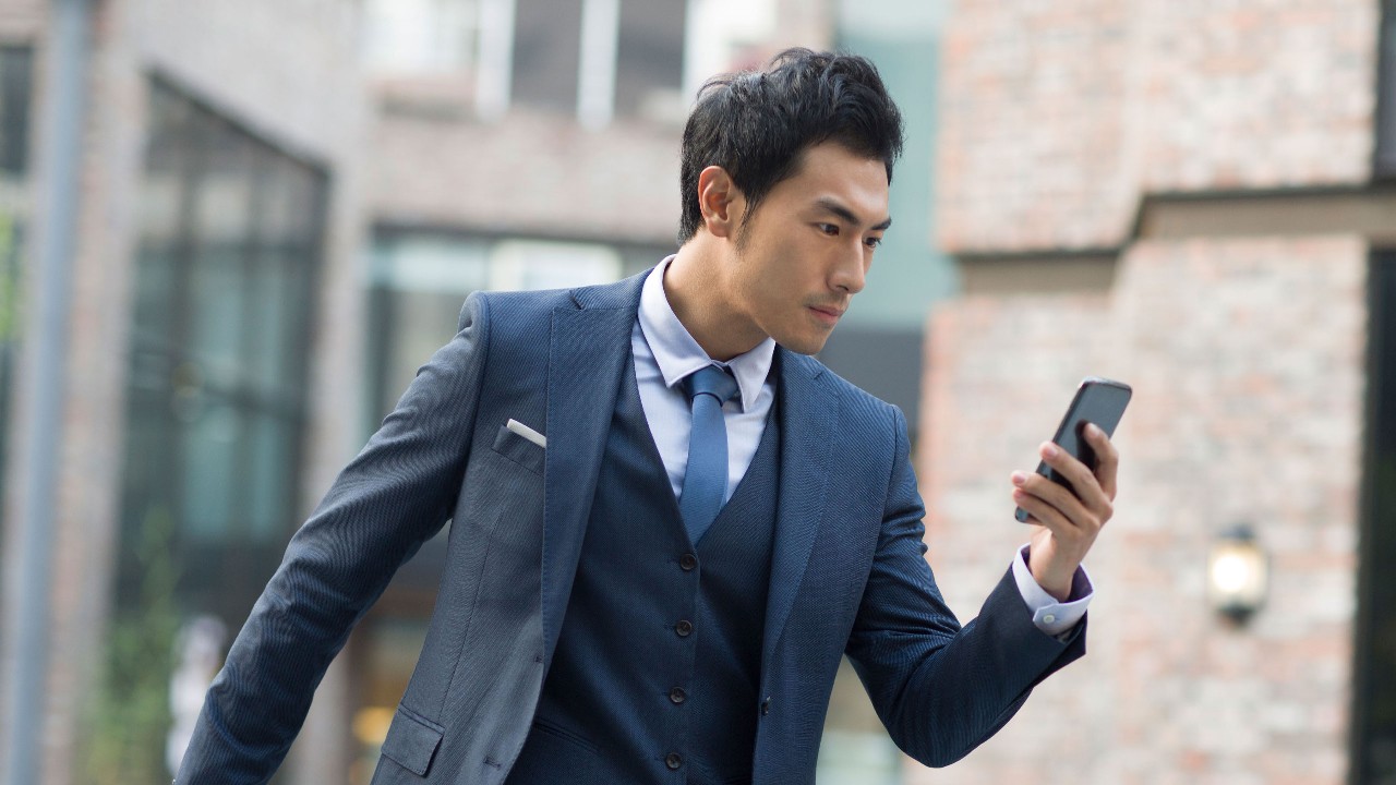 Businessman use his smartphone to read the latest news; image used for "Time Saver" article.