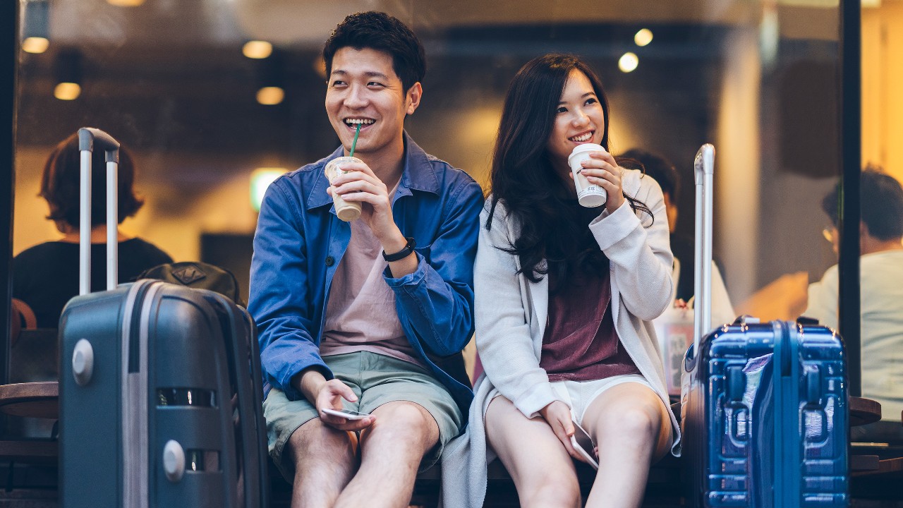 Cheerful couple enjoying their take-away coffee while waiting to board a flight;image used for HSBC Capital Protected Investment - Currency Linked III